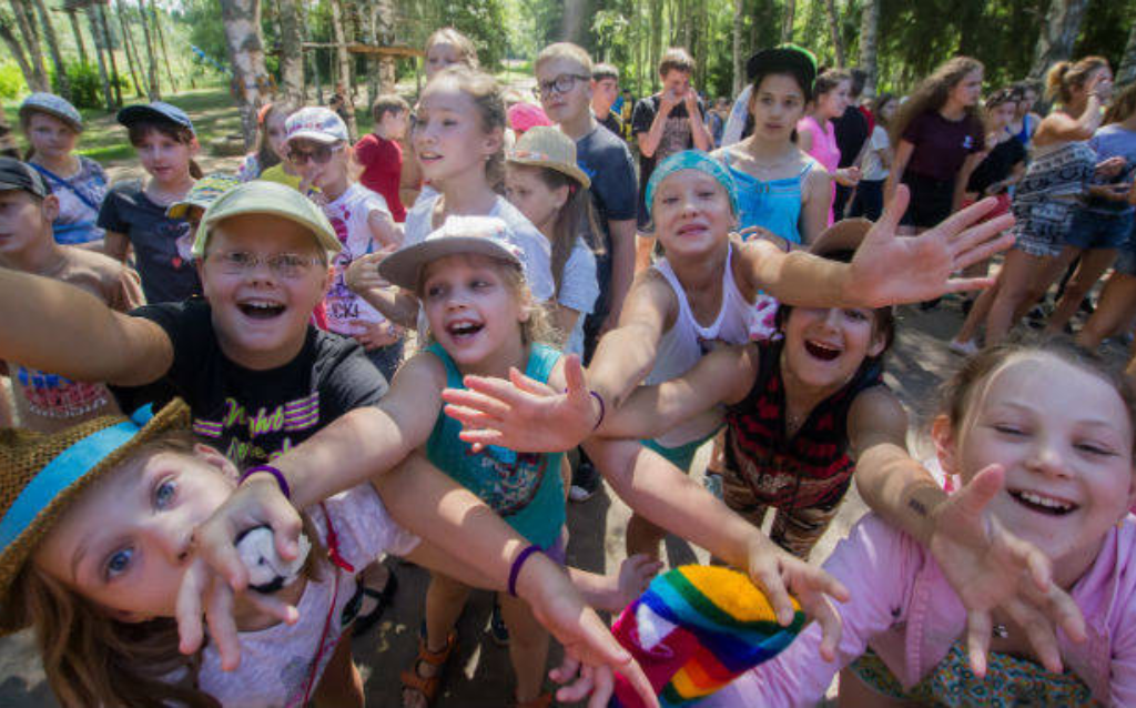 Grupo de niños riendo y jugando en una fiesta infantil inclusiva al aire libre, fomentando amistad y participación.